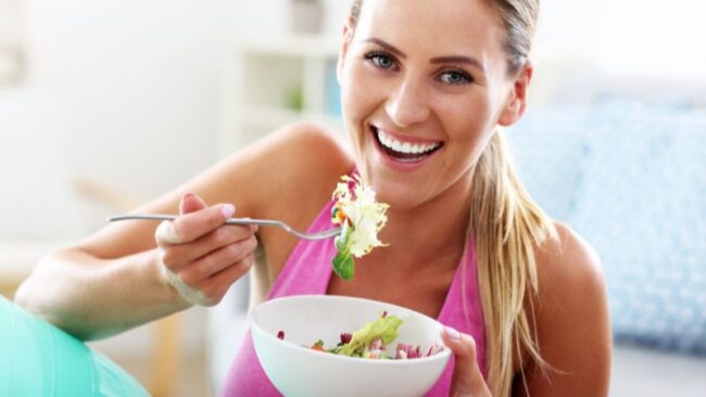 sommergewicht halten FJunge Frau isst einen Salat als gesunde Mahlzeit zum Abnehmen