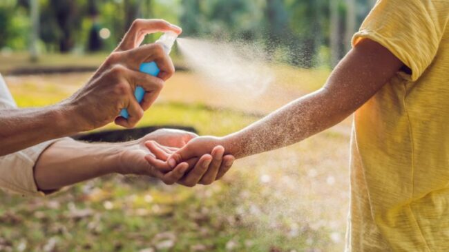 Plagegeister adé: So schützen Sie sich im Sommer vor Insekten frau sprüht gelsenspray auf einen kinderarm