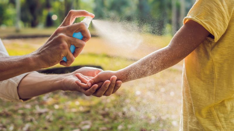frau sprüht gelsenspray auf einen kinderarm
