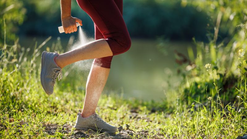 Joggerin sprüht sich Insektenschutz auf ihre nackten Unterbeine